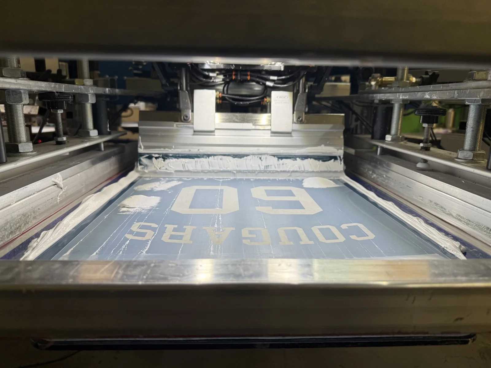 Close-up of a silkscreen flooded with ink on the press
